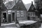 Foto av traditionell holländsk arkitektur, med sina rad-hus som kantar vattendrag och gränder, en typisk byggnadsstil som dominerade under 1900-talet med en kvinna som sitter vid vattnet, 1924-25.