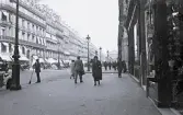 Foto av en gata i Paris med byggnader och strosande människor, 1924-25.