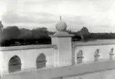 Museets kommentar: Kort efter reparationen 1927 monterades pompösa lyktor på stenkloten, dessa monterades ner 1934 efter det kom solurets pinne aldrig på plats igen. Därför måste denna bild vara tagen just när bron är nyreparerad. Se även post nr 01460.  Enl text i Antivariskt- Topografiska-Arkivet (ATA) kom lyktorna upp 1931.