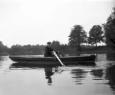 En ung man i roddbåt på sjön.