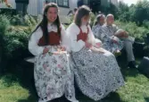 Spelmansstämma på hembygdsgården Börjesgården i Hällesåker, Lindome, i Mölndals kommun den 8 juli 2000. Två kvinnor införda bygdedräkt sitter och intar en måltid.