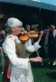 Spelmansstämma på hembygdsgården Börjesgården i Hällesåker, Lindome, i Mölndals kommun den 8 juli 2000. En kvinna införd bygdedräkt spelar fiol.