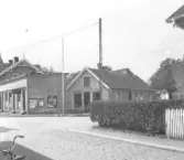 På skyltarna kan man läsa, Skomakeri A&E WASS, Olympia, Storan och Folkparken.  Byggnaderna till vänster revs 1973, de till höger fanns 1938 men inte 1945.
