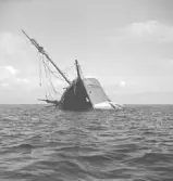 Vraket av segelskutan Zemita av Helleviksstrand. Strandade norr om Stuten vid Skomakarehamnen natten till den 15 aug 1966. På fotot har hon ståt på grund ett tag innan stormarna bryter sönder henne. Familj den amerikanske atomprofessorn Alexander Szerlips seglade båten, de skulle segla jorden runt från Sverige men kom ej längre än till Veijle. Familjen två vuxna och två barn räddades av lotsbåten från Falkenberg.   Fotot tagit från Agevik.