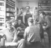 Foto 1. Gruppbild - Nio skoarbetare på sulstansningsavd. vid Ljungsko skofabrik har rast och är sysselsatta med att spela kort.   Längst bak t.v. Anders Andersson, Karl-Erik Larsson,okänd, Arvid Bengtsson, längst ned t.h. Gert Johansson sitter med kort i handen. Med ryggen åt fotografen, Ove Karlsson till vänster, bakom honom Lilly.  Foto 2 o. 3 Rast och kortspel.