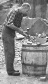 Stenhuggare Gunnar Karlsson, Haverdal, Harplinge putsar gatsten med kantjärn på trätunna i stenbrott i Vastadalen.