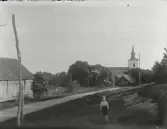Till v syns kyrkstallarna som numera är rivna, framför kyrkan syns skolans uthus. Ev är det Per Persson på bilden.  A Fridolf Persson var lärare i Årstad 1904-1912, Fritsla 1912-1920, Släp 1921-27 och Skrea 1927-41. Enl. sonen Einar Persson.