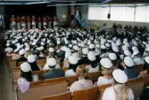 Studentexamen på Fässbergsgymnasiet i Mölndal den 7 juni 2000. Studenterna har samlats i skolans aula. På scenen uppträder Mölndals Paradorkester.