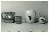 Tre kannor och en mugg från Bo Fajans, formgivare Eva Jancke-Björk, 1900-talets mitt. Kannan och muggen till höger i bild har en relief som dekor.