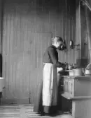 Augusta Nilsson står vid spisen och lagar mat.