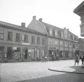 Vy utmed Storgatan (kv. Stormen) med bl a Foto-Centralen och ingången till Vigfors matsalar, följt av Monarks cykelaffär.
Till höger anar man takutsprånget till Cigarr-Olles tobakshandel mittemot, i kvarteret Nunnan.