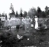 Foto av bivacken vid Mårdnäs beväringsrekrytskolan med både män och kvinnor, det ser ut som dom ska laga mat till beväringarna, 1901