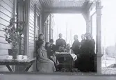 Foto av män och kvinnor som sitter på verandan till Borgsjö prästgård.