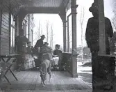 Foto av män och kvinnor samt en hund som sitter på verandan till Borgsjö prästgård.