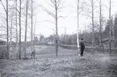 Foto av två män som ser ut att göra någon form av mätning på marken vid Borgsjö. Text i album: 