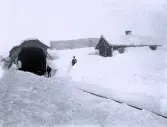 Foto av en snötäckt järnvägstunnel med män som står vid sidan om spåret. Text i album: 