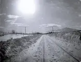 Foto av ett snötäckt järnvägsspår en solig vinterdag i fjällen.