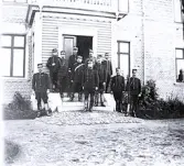 Foto av en grupp militärer som står vid en trappa till en byggnad. Text i album: 