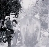 Foto av militärer som ska sitta upp på häst vid fältövningar.