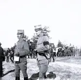 Foto av militärer som är ute på fältövningar med hästar i bakgrunden. Text i album: 