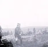 Foto av två militärer som utövar övning i fält någonstans på landsbygden. Text i album: 