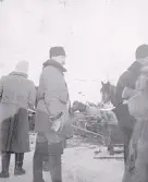 Foto av vinterklädda militärer under arméfördelningens fältövningar 1905, i bakgrunden syns hästar med vagnar. Text i album: