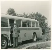 En SJ-buss har stannat till någonstans på landet utanför Växjö (?) (Kronobergshed?). 
På sidan kan man otydligt läsa: 