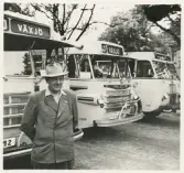 En man i kavaj och hatt står framför några SJ-bussar, i närheten av järnvägsstationen, Växjö.
I bakgrunden skymtar dåv. hotell Savoys fastighet vid Norra Järnvägsgatan.