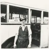 En man i skjorta, väst och skärmmössa står framför en SJ-buss  trol. i närheten av järnvägsstationen, Växjö.