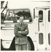 En man i kostym och slips står vid sidan av en buss, trol. i närheten av järnvägsstationen, Växjö.