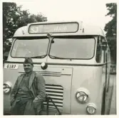 En chaufför i kavaj och båtmössa står framför en SJ-buss, trol. i närheten av järnvägsstationen, Växjö.