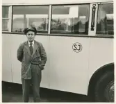 En chaufför i kavaj och skärmmössa står invid en SJ-buss, trol. på busstorget/järnvägsplan vid järnvägsstationen, Växjö.