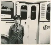 En chaufför i kavaj, slips och skärmmössa står invid en SJ-buss, trol. på busstorget/järnvägsplan vid järnvägsstationen, Växjö.