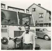 En chaufför i cardigan och fluga står framför en SJ-buss , trol. vid Norra Järnvägsgatan, Växjö.