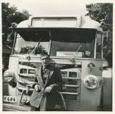 En chaufför i uniformskavaj och skärmmössa poserar framför en SJ-buss , trol.  på Norra Järnvägsgatan i närheten av busstorget/järnvägsplan i Växjö.