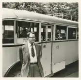 En chaufför i kavajkostym, slips och glasögon poserar bredvid en SJ-buss, möjl. på busstorget/järnvägsplan i Växjö.
På skylten bakom honom kan man läsa: 