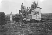 Anderstorps Stormosse ca 1941.Torvtäkt bedrevs här under andra världskriget. Täkten och de många diken som då grävdes på flera platser gjorde att delar av mossen torkade ut och blev trädklädd under andra halvan av 1900-talet. Arbetare vid en torvmaskin med transformator och verktygslåda är: Ingrid Magnusson vid linbanan, Anna-Britt Salomonsson gift Ljungberg inne i maskinen, Alrik Salomonsson från Gunillabo högst upp till vänster, Ragnar Hjelm med kepsen på sned, 3 bröder Johansson från Mossebo.