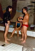 Medlemmar i Lindome Sportdykarklubb övar dykning i Åby simhall i Åby, Mölndal, år 1983. Två män samtalar vid bassängkanten.