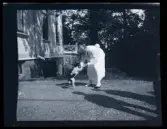 En kvinna leker med en hund utanför villa Solveden, Djursholm.