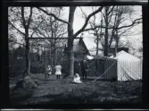 Leonarth, Birger, Gunnar, Elsa och Gudrun leker vid gungorna intill ett litet randigt tält i trädgården till familjen Morthensens villa Solveden, Djursholm.