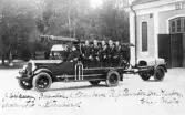 Brandkårens utryckningsvagn med manskap framför brandstationen på Köpmantorget i Söderhamn. Foto troligen 1920-tal.