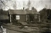 Här bodde Erik Andersson, kallad Kloar-Erik. Erik föddes år 1900 och bodde här i Veddige som fattig hemmason med sin mor, Inger ”Kloar-Inger” Andersdotter, tills hon dog 1945. Därefter bodde Erik kvar ensam tills han själv gick bort 1966. Stugan låg på ofri grund långt upp i skogen ovanför Järlövs gård. Han köpte sin första kamera via postorder på 1930-talet, monterade själv ihop den och gick eller cyklade sedan omkring året runt i trakten och fotade vad som kom i hans väg.