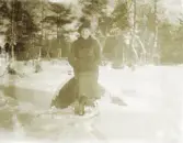 En ung kvinna på vintrig promenad, har slagit sig ner på en sten i en slänt.