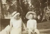 En ung kvinna och en pojke i linne, spetsmössa och stråhatt.
Trol. Kristina Nilsson (1898-1973) och hennes bror Benno (1904-1995), Gårdsby säteri.