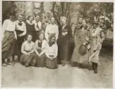 En seminarieklass med blivande lärarinnor på skolgården till dåv. Norra seminariet, Växjö (nuv. Ringsbergsskolan). Deras klassföreståndare syns i mitten. I bakgrunden syns (trol.) Mariahemmets baksida.
Något suddigt foto.