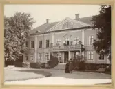 Vy mot huvudbyggnaden på Östrabo. Nedanför trappan står biskop Johan Andersson med fru Elise.
Under fotot en dedikation: 