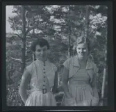 Två unga kvinnor, båda iklädda randiga klänningar.