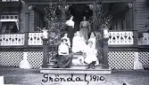 Foto av kvinnor och barn som sitter framför verandan på Gröndal, 1910. Text baksida kort: 