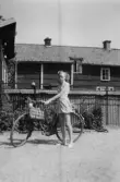 Flicka med cykel framför hus
