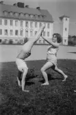 Två skolungdomar gymnastiserar framför Almby skola, 1945
